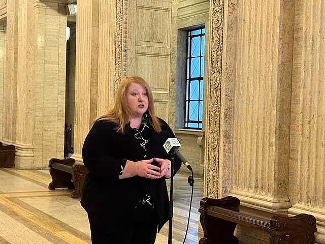 Naomi Long speaking into microphones at Stormont