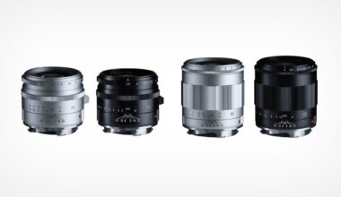 Four camera lenses are arranged in a row on a white background, with two lenses in silver and two in black. The lenses are compact and have visible focus and aperture markings.