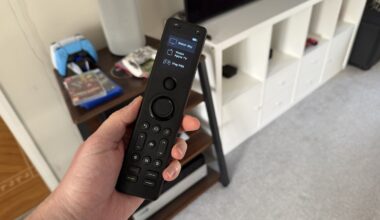 A photo of someone holding a Sofabaton X1S remote control in a living room