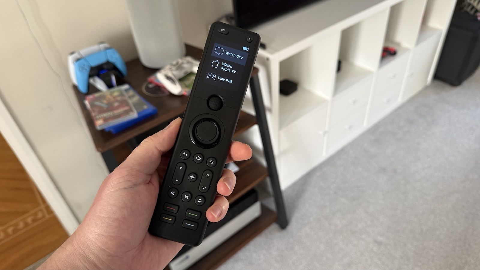 A photo of someone holding a Sofabaton X1S remote control in a living room