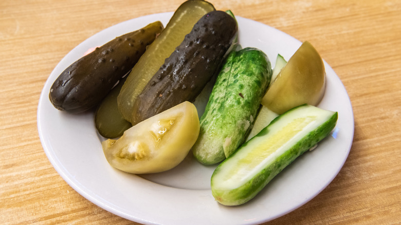 Pickles and pickled tomatoes on a white plate