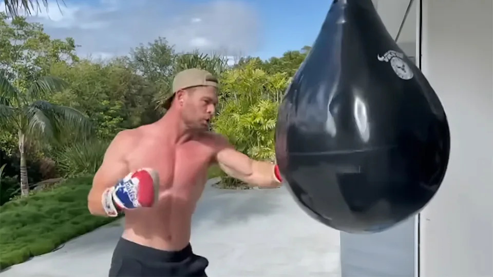 Chris Hemsworth hitting a big black bag to refine his abs. 