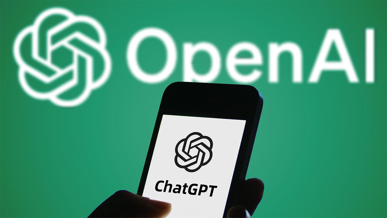 Smartphone displaying ChatGPT logo held in front of white OpenAI logo on green background