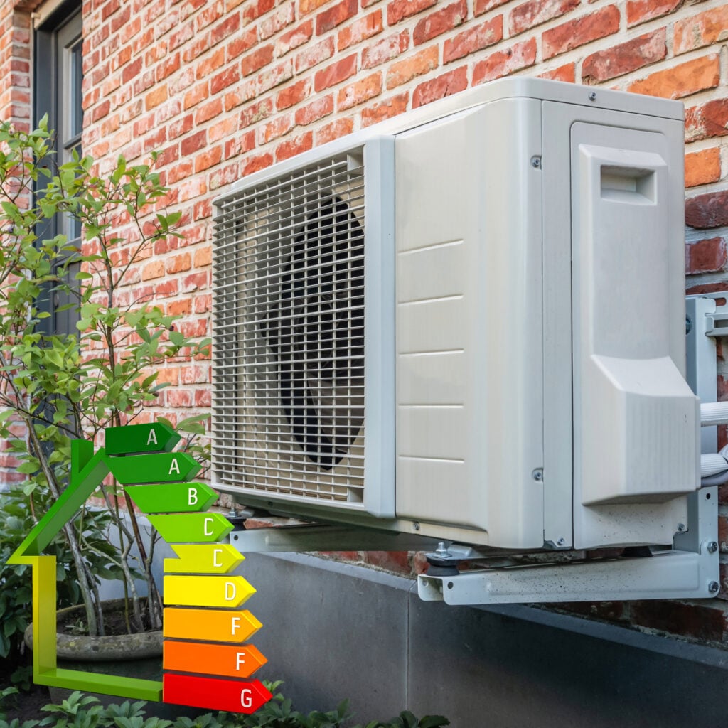 Air source heat pump installed on an exterior brick wall with energy efficiency rating graphic
