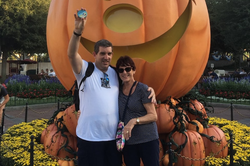 Man and woman in front of Disney carved pumpkin