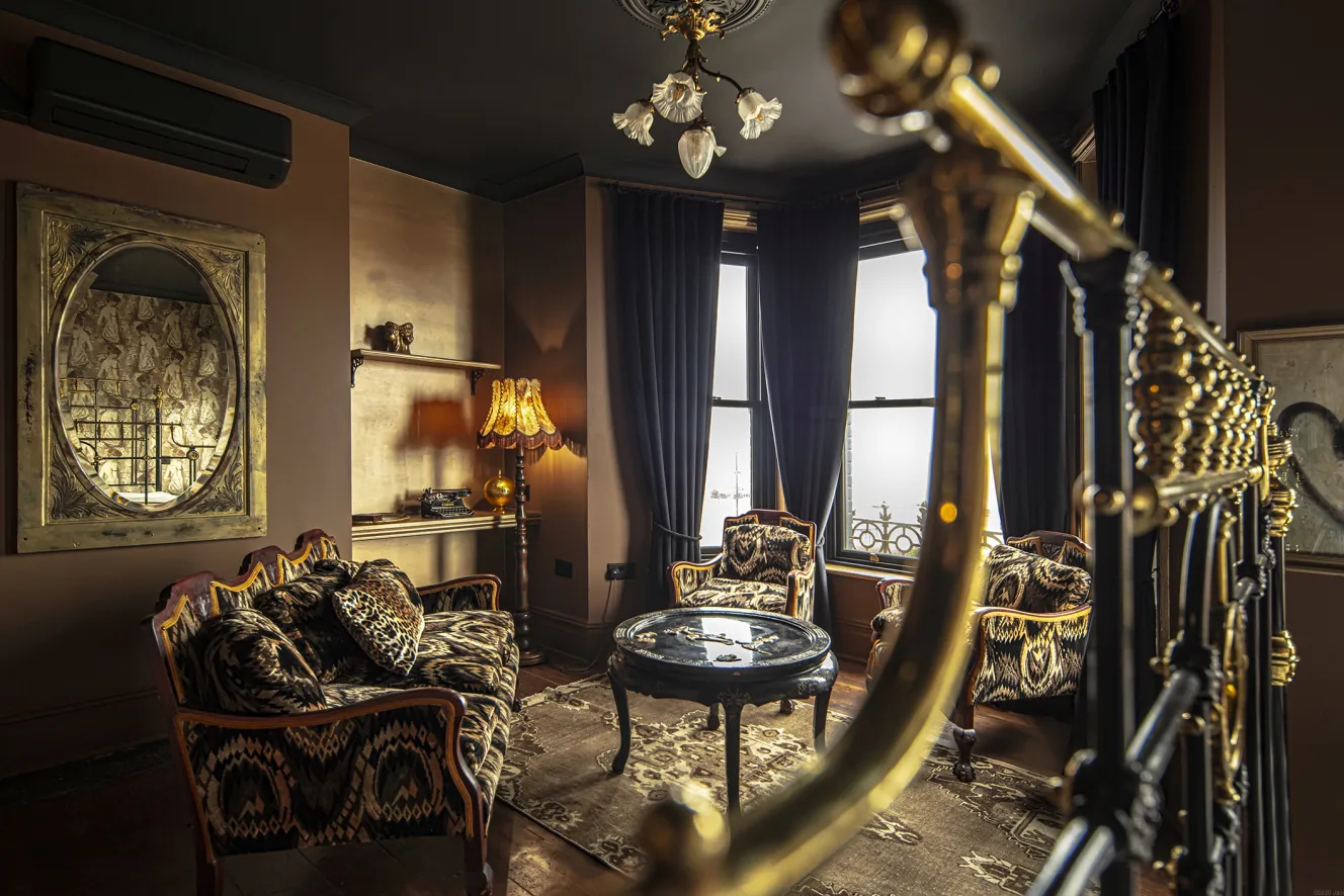 A sitting room at The Albion Rooms with patterned furniture, a black coffee table, and a large mirror.