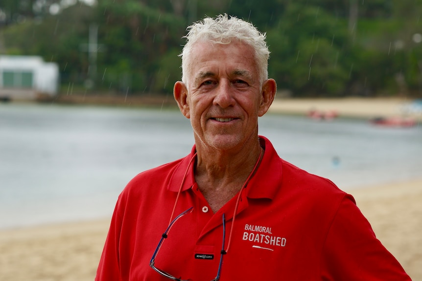 Steven Hedge has grey hair and a bright shirt and poses for a photo on a beach.