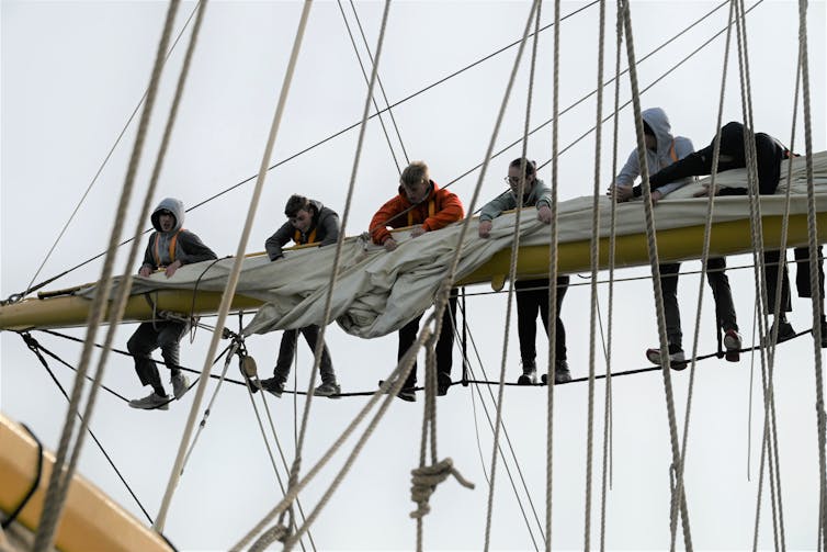 six teenagers up mast of sailing ship