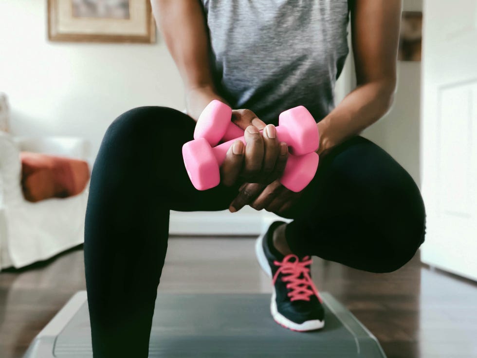 Woman Works Out at Home close up of unrecognizable black woman working out at home with dumbbells and aerobic step