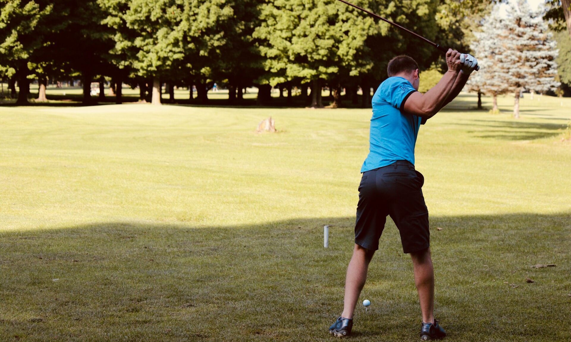 A person taking a swing on a golf course.