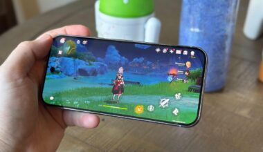 A smartphone playing an adventure game, Genshin Impact, in front of a table background.