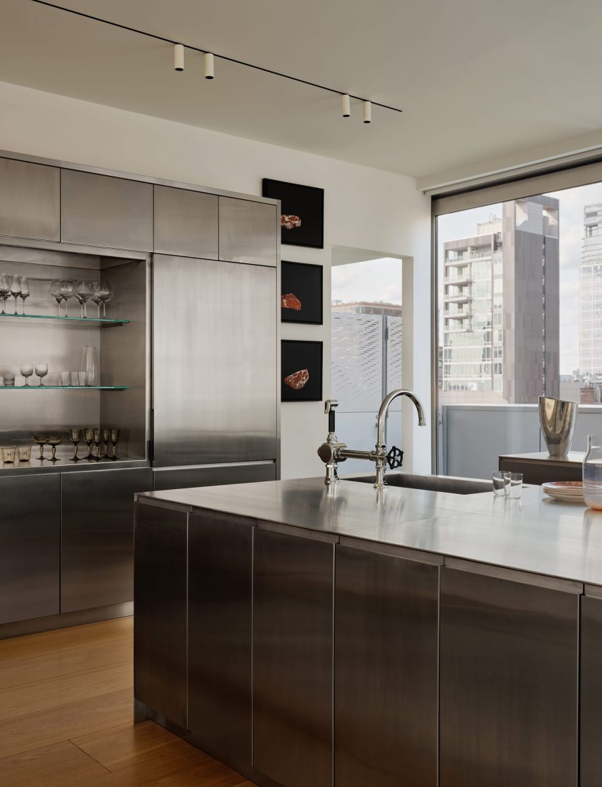 A stainless steel kitchen featuring three custom-designed monolithic elements