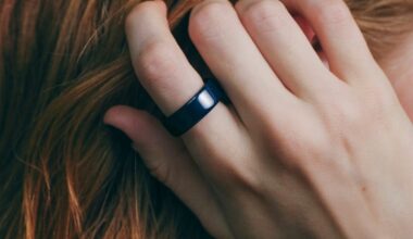 A close-up of the navy Oura Ring on a hand running through red hair.