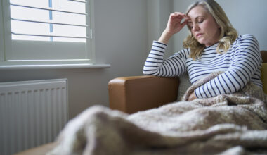 Mature Economically Inactive Woman Suffering With Long Term Illness Sitting On Sofa At Home