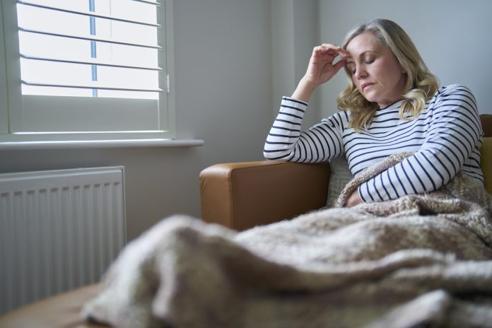 Mature Economically Inactive Woman Suffering With Long Term Illness Sitting On Sofa At Home