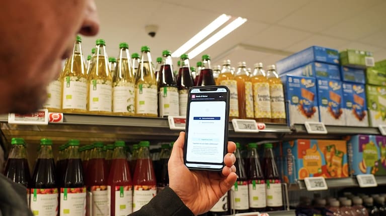 Ian Rosenfeldt, the creator of "Made O'Meter" mobile app, demonstrates how shoppers can use the application to identify and boycott American goods in a grocery store in Copenhagen.