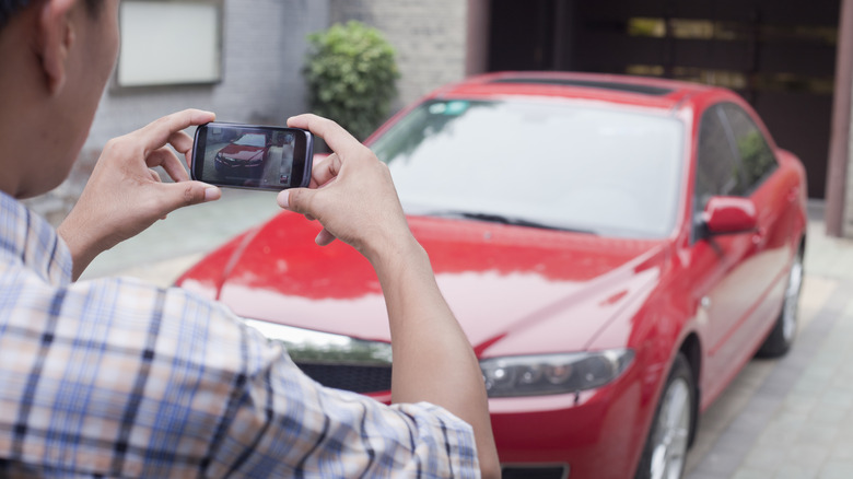 Person taking a picture of a car