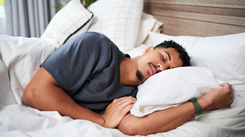 A man sleeping on a bed with white sheets