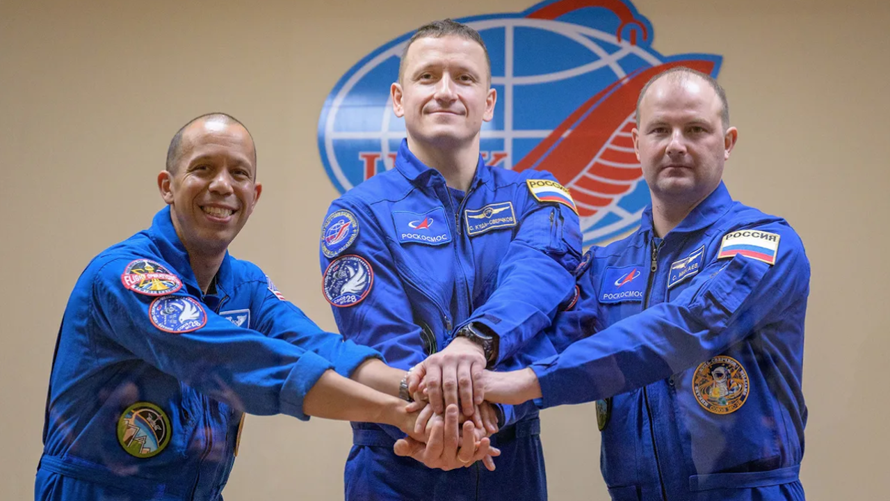 Three astronauts wearing blue flight suits