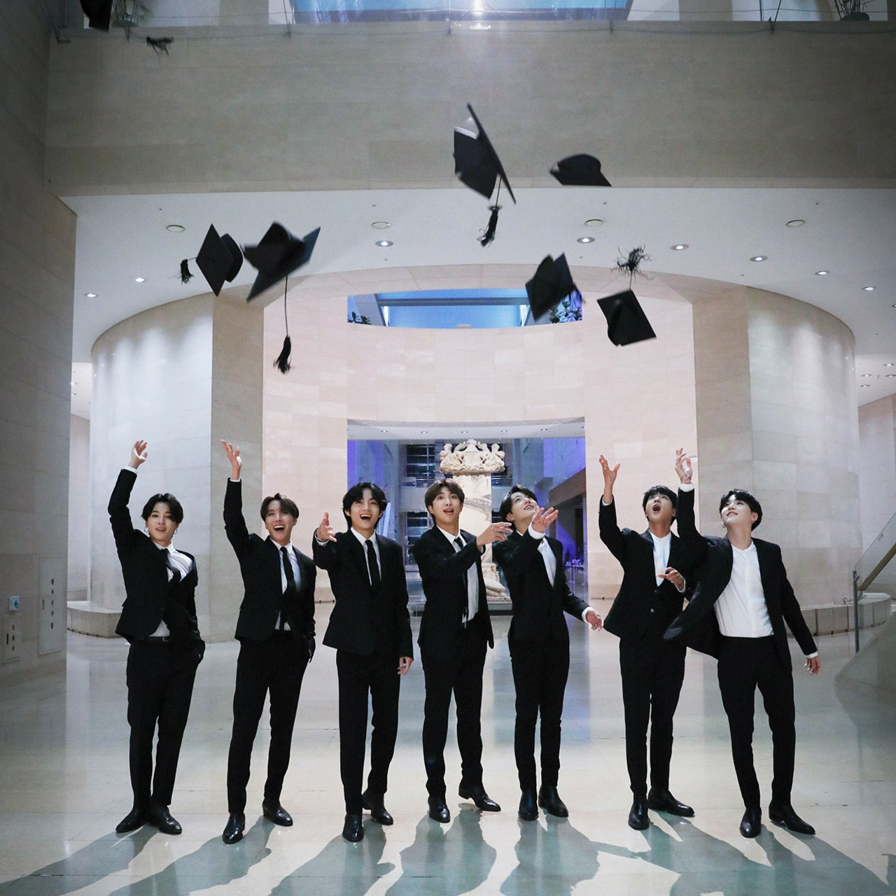 The BTS members throw graduation caps into the air at the National Museum of Korea for YouTube's "Dear Class of 2020" campaign. (National Museum of Korea)