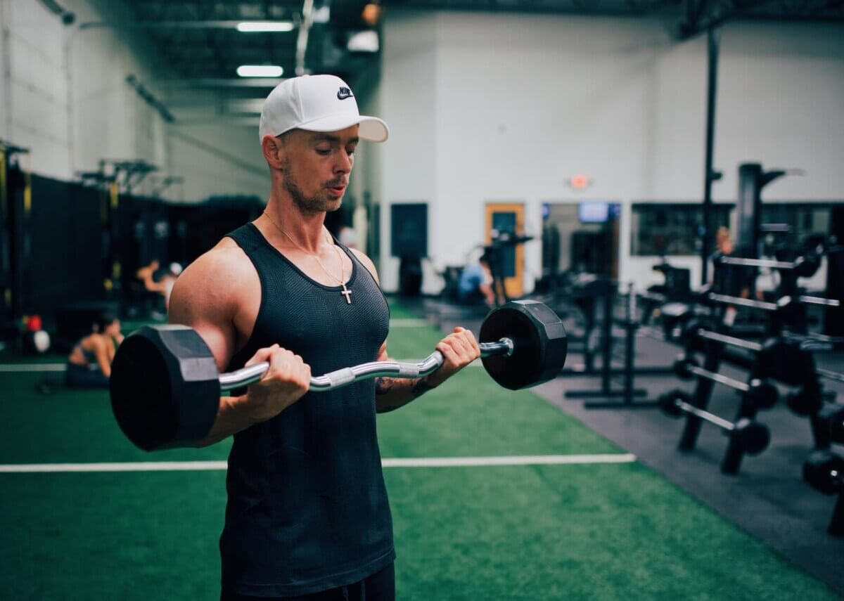 Man doing bicep curls while weightlifting in a gym.
