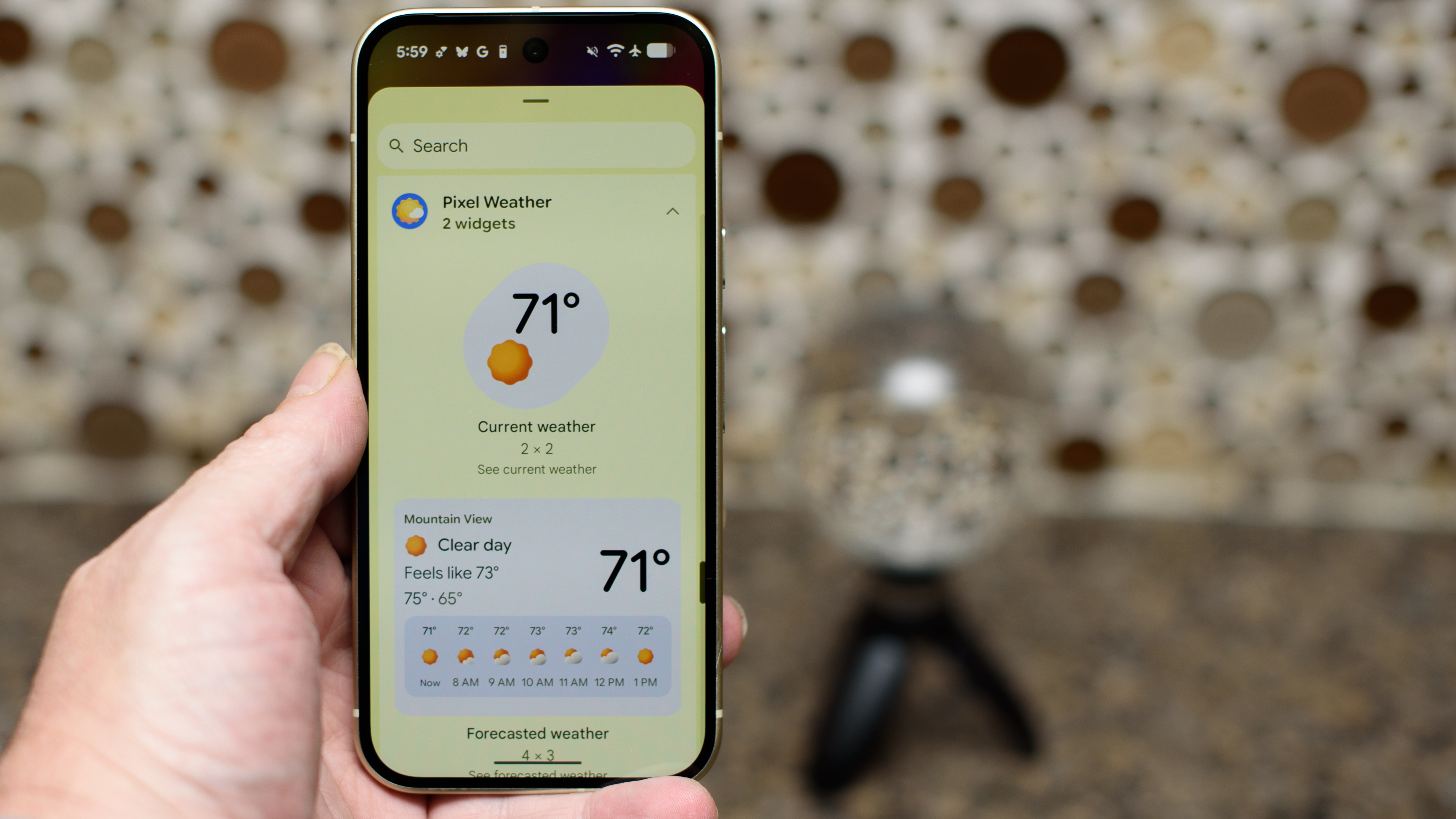 Google Pixel 10 in Lemongrass against a bubbly backsplash