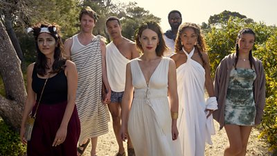A group in homemade fancy dress costumes walk up a path on a sunny day. They all look towards the camera. 