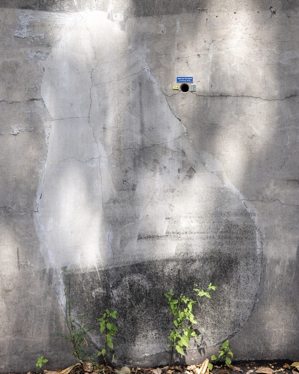 A miniature installation by Michael Pederson of tiny signs installed next to a circular hole in a concrete wall, which read