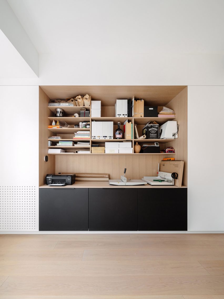 A wood-lined recess in an all-white wall that's used to store office equipment