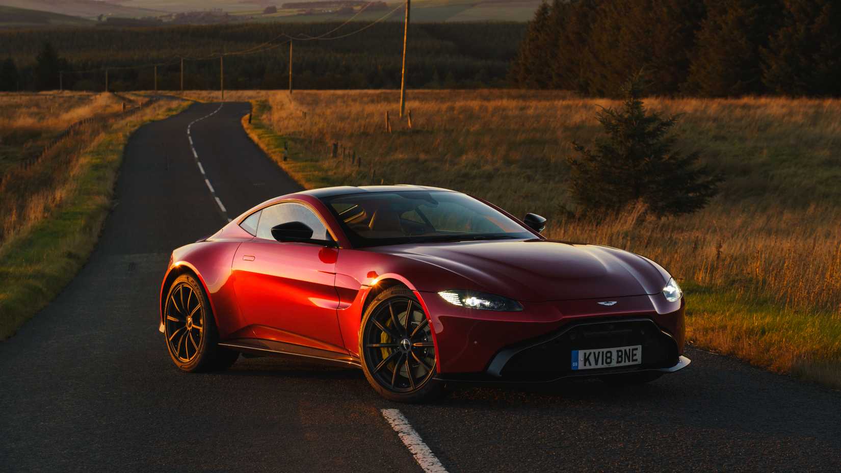 Red Aston Martin Vantage 550 on a deserted country road at sunset