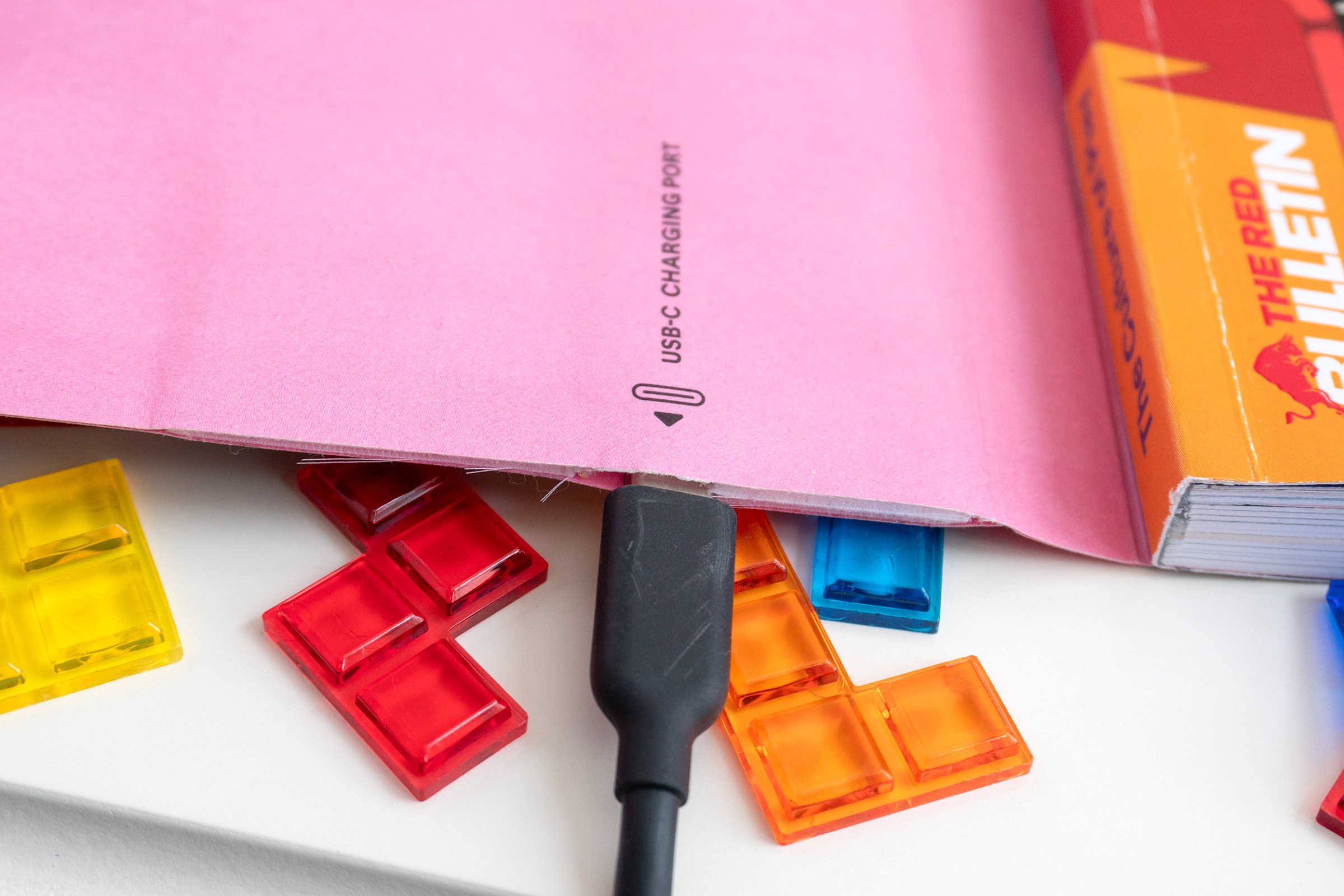 A close-up of a USB-C cable plugged into a charging port on the bottom of a magazine cover.