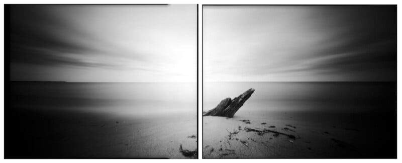 Black and white diptych photo of a calm beach with smooth water and cloudy sky; a large piece of driftwood is embedded in the sand on the right panel, creating a tranquil, minimalist seascape.