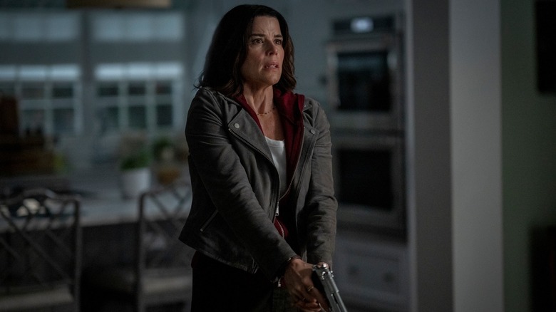 Neve Campbell as Sidney Prescott with a gun out in the kitchen in Scream 7