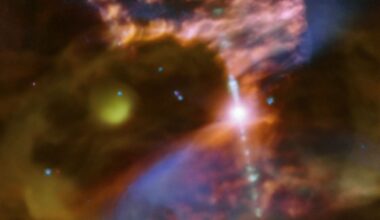 A blurry swirl of blue and yellow and red gas are seen in this image with a bright dot of light in the center