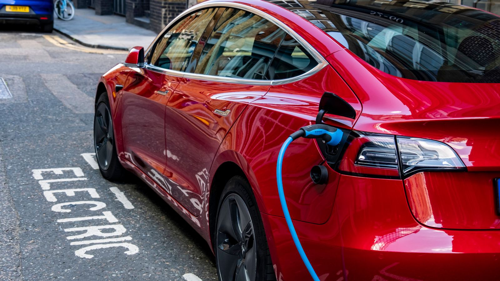 A red Tesla Model 3, with hidden door handles, parked and charging in a designated charging bay in central London. Pic: iStock