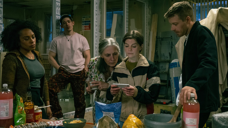 Lou, Roddy, Standish, Shirley, and River all looking at a phone in Slow Horses