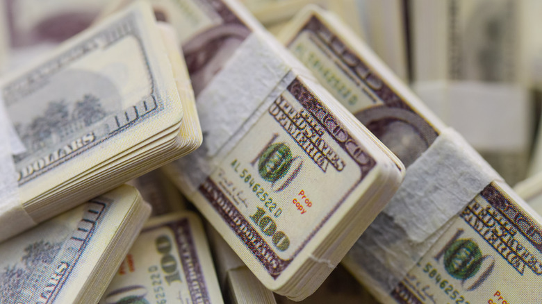 Close-up of stacks of 100 dollar bills, multiple stacks on top of each other, other bills visible in background