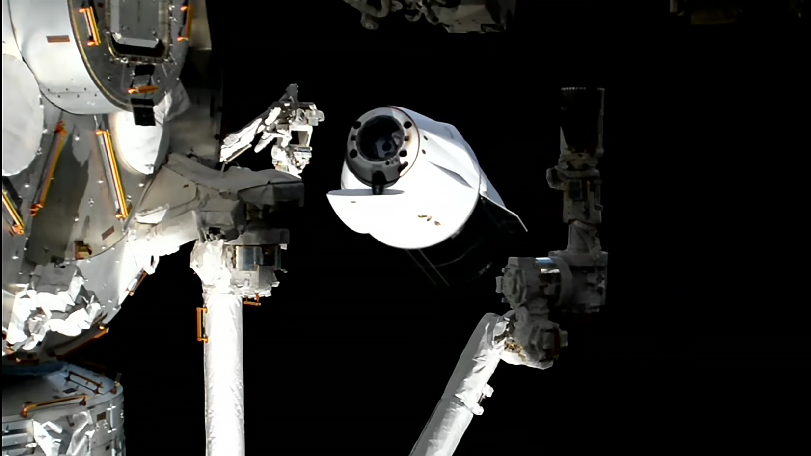A SpaceX Dragon (center) backs away from the International Space Station after undocking from the Harmony module's forward port.