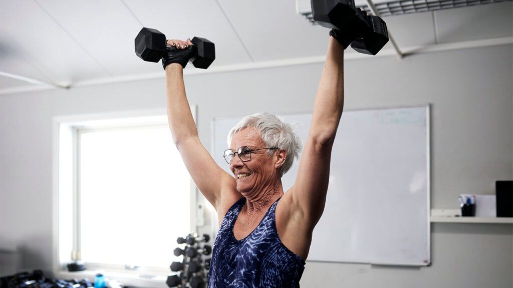 An older female exercising with dumbbells.