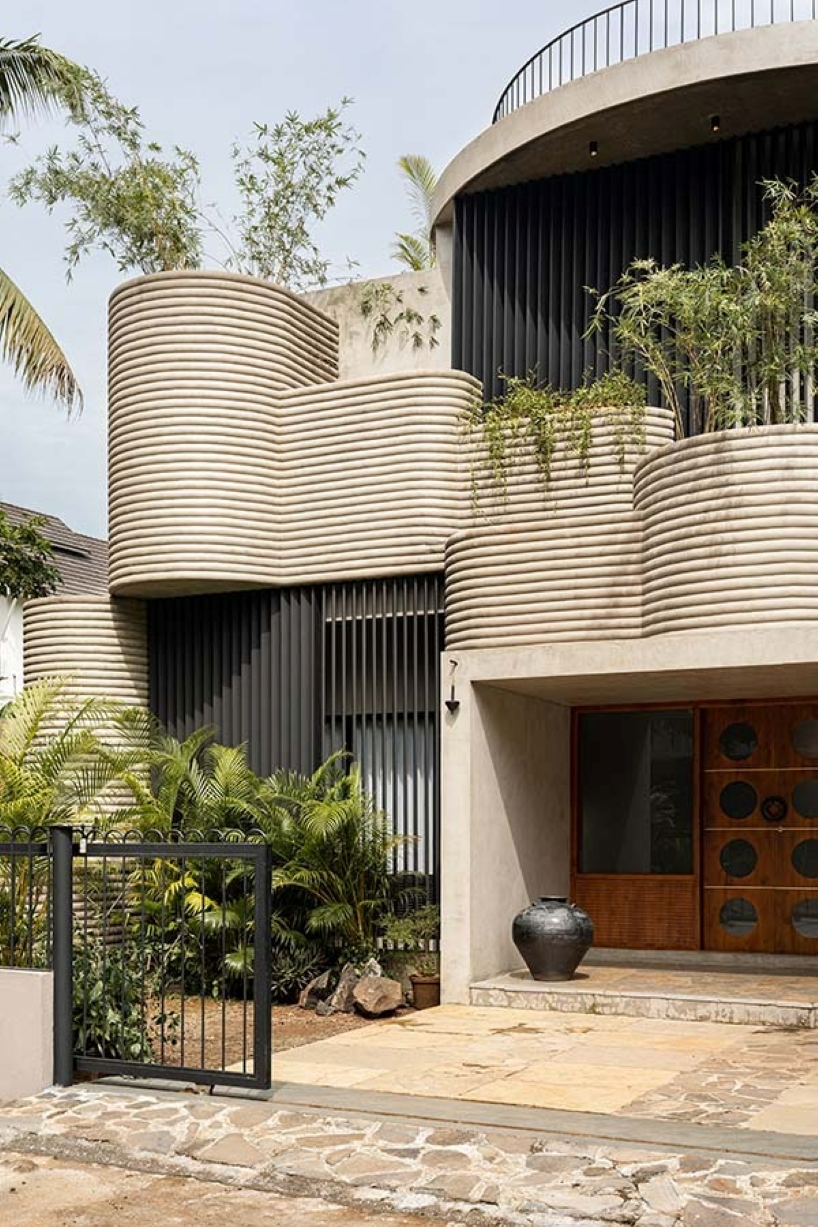 circular green terraces carve through exposed concrete facade in india