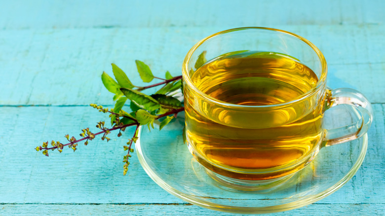 A cup of tulsi tea on a wooden turquoise table