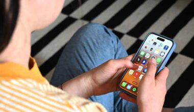 A person in a striped yellow shirt using an iPhone.