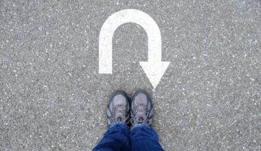 A person standing with a u turn sign on the ground in front of them.