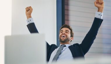 An investor cheers behind a laptop.