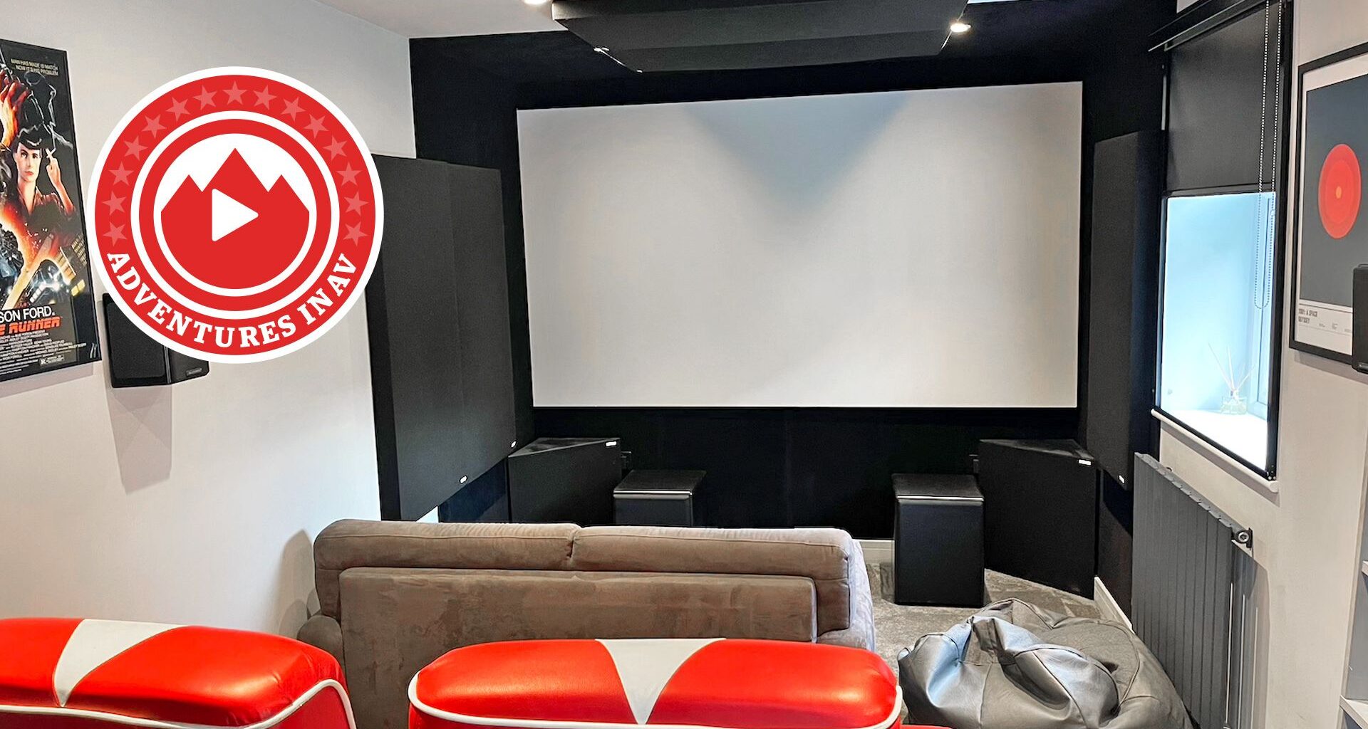 A photo of a dedicated home cinema room with red chairs and a Blade Runner poster on the wall