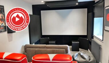 A photo of a dedicated home cinema room with red chairs and a Blade Runner poster on the wall