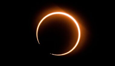 The outline of the sun is visible surrounding the moon during a solar eclipse, with a small break in the circle to the lower left.