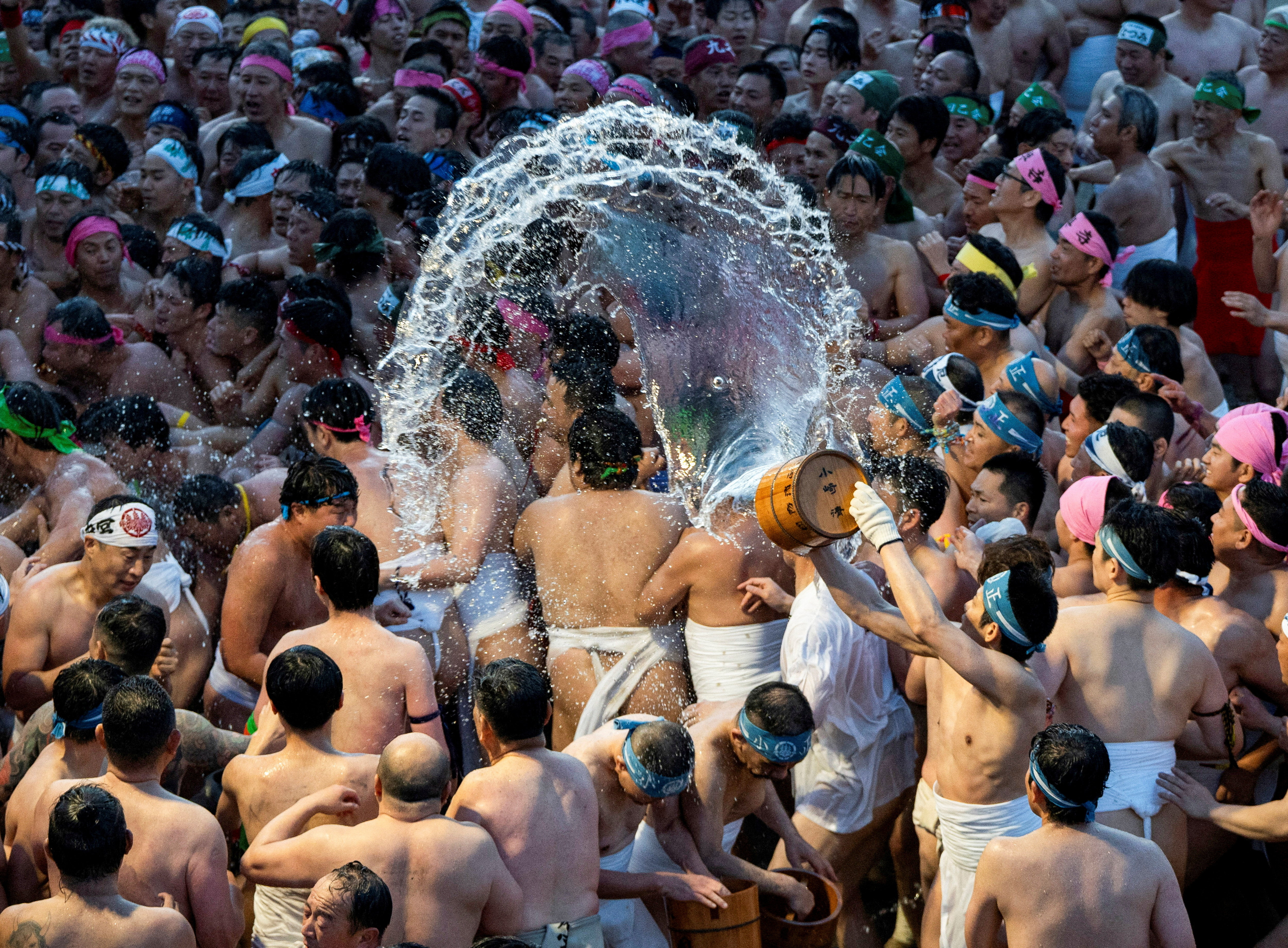 Men in loincloths and headbands splash water at the Konomiya Naked Festival.