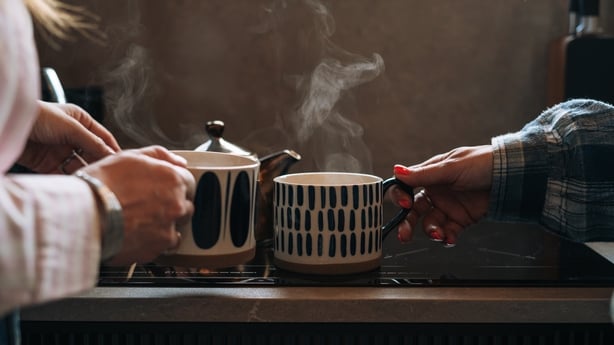 Friends of a middle-aged woman drink tea and talk in the kitchen in the house