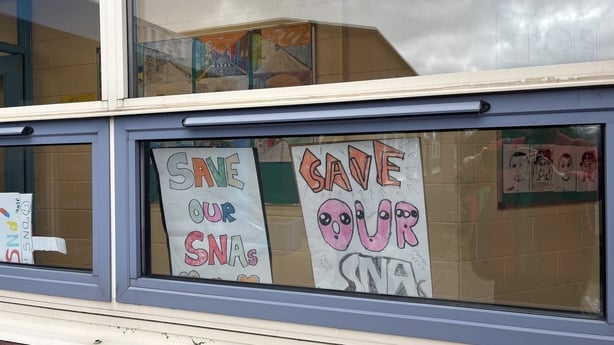 two signs in a window with colourful writing and the words 'save our SNAs'